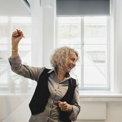 Frau, die lächelt und am Whiteboard schreibt.